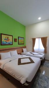 a room with three beds with green walls at The Cabin Hotel Sidoarum in Sleman