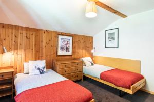 two beds in a room with wood paneling at Mont Gele Hotel in Verbier +1 photo