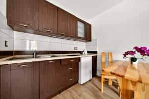 a kitchen with wooden cabinets and a wooden table at Domek u Świerków - apartamenty z aneksami i pokoje z mini lodówką blisko Term Chocholowskich in Chochołów