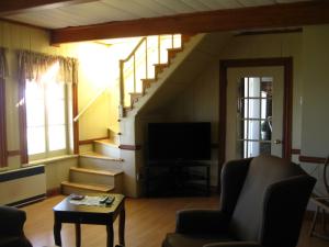 a living room with a staircase and a television at Gite la Maison Rochefort in Baie-Sainte-Catherine