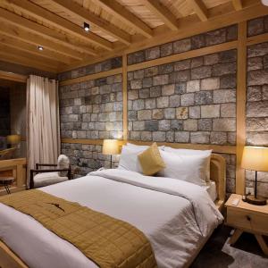 a bedroom with a bed and a brick wall at Dera Lamsa Resort Shigar in Shigar
