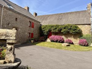 a stone building with pink flowers in front of it at Des puits in Locoal-Mendon