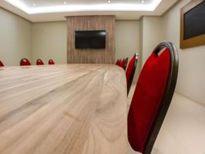 a conference room with a long table and red chairs at ibis Imperatriz in Imperatriz