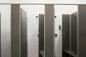 a bathroom with two stalls with mirrors and white tiles at The Cally Hotel in Warrnambool