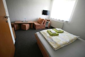 a bedroom with a bed and a chair and a table at Penzion Ajda in Liptovský Mikuláš