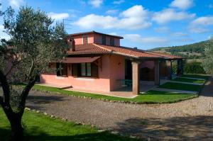 a pink house with a tree in front of it at Agriturismo Radicata in Capalbio