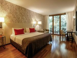 a bedroom with a large bed with red pillows at Mercure Iguazu Hotel Iru in Puerto Iguazú