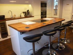 a kitchen with a counter with stools at a island at Kings House Wokingham in Wokingham