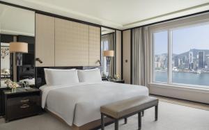 a bedroom with a large bed and a large window at The Peninsula Hong Kong in Hong Kong