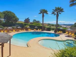 a swimming pool with chairs and palm trees at Villa Sunrise by MOJE Holiday in Budens +32 photos