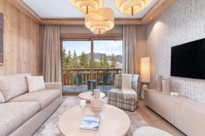 a living room with a couch and a tv at Barma Résidence & Appartements in Courchevel