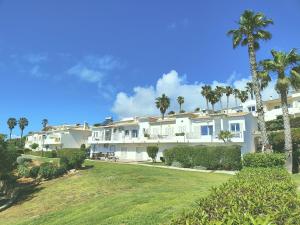 a large white building with palm trees and a yard at Villa Sunrise by MOJE Holiday in Budens