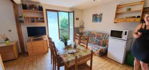 a woman standing in a living room with a table and a kitchen at Les Crêtes studio divisible by Mountain Collection Immobilier in Le Monêtier-les-Bains