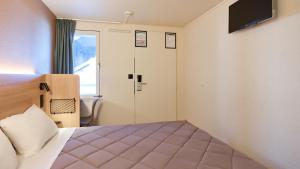 a hotel room with a bed and a sliding door at Premiere Classe Bayonne in Bayonne