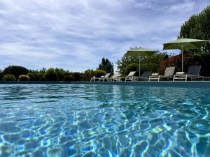 a swimming pool with chairs and umbrellas at Ermitage De Corton - Teritoria in Chorey-lès-Beaune