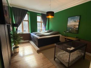 a bedroom with a bed and a green wall at Greenbrook - Black Suite in Aalborg