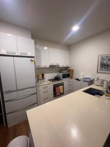 a kitchen with white cabinets and a white refrigerator at Spacious Master Room with Private Ensuite in Melbourne