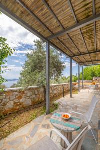 a patio with a table and chairs and a stone wall at Kalokairi Boutique Residence in Skopelos Town