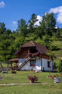 a house with a porch and a staircase in a yard at Dolina Vekova in Banja