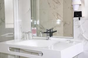 a bathroom with a white sink and a mirror at Hôtel Saint Sauveur in Lourdes +27 photos
