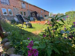 a garden with a chair and flowers in front of a brick building at Ferienhof Uckermark am Oberuckersee in Suckow