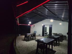 a group of tables and chairs in a room at night at Heijo's Travellers Nest in Jarain