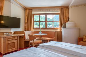 a hotel room with a bed and a desk and a tv at Natur & Alpinhotel Post in Vent