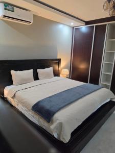 a bedroom with a large bed with a blue blanket at Ednomis Apartment in Mazabuka