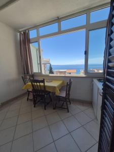 a dining room with a table and chairs and a window at Guest House Čović in Tučepi