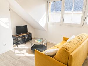 a living room with a yellow couch and a tv at Duplex de charme au coeur de Beaugency in Beaugency