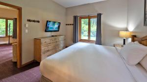 a bedroom with a large white bed and a television at Cahilty #149 in Sun Peaks +15 photos