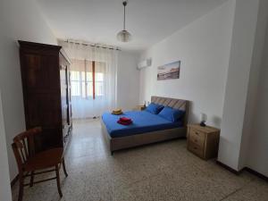 a bedroom with a blue bed and a chair at Casa Bonaria in Terralba