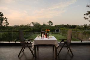 a table with a white table cloth and two chairs at Saffronstays Olive Farms in Mandkaula