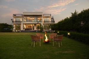 a house with chairs and a fire pit in the yard at Saffronstays Olive Farms in Mandkaula