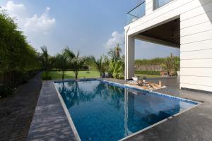 a swimming pool in a backyard with a house at Saffronstays Olive Farms in Mandkaula