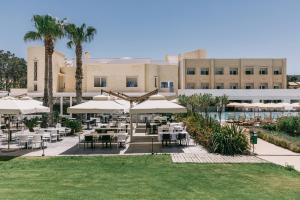 a restaurant with tables and umbrellas in front of a building at Mangia's Himera Resort in Campofelice di Roccella