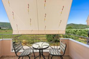 a balcony with two chairs and a table at VALERIA Apartment in Vonitsa