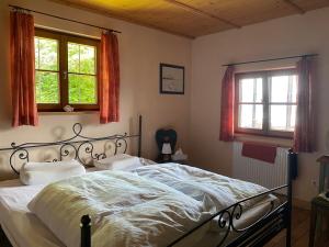 a bed in a bedroom with two windows at Seehaus Simssee in Stephanskirchen