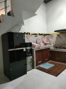 a kitchen with a black refrigerator and a sink at Homestay Berlian T in Alastuwo