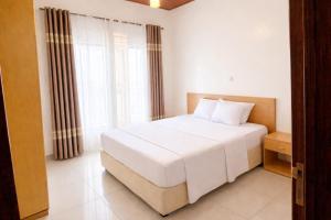 a bedroom with a white bed and a large window at KIGALI FANTASTIC Aparthotel in Kigali