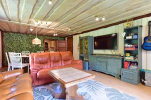 a living room with a couch and a tv at 4gilės sodyba Alytaus rajone in Kružiūnai