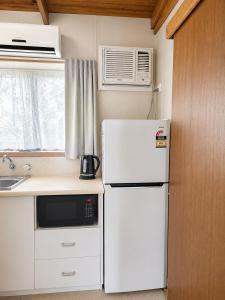 a small kitchen with a refrigerator and a microwave at Shady Acres Caravan Park in Warrenheip
