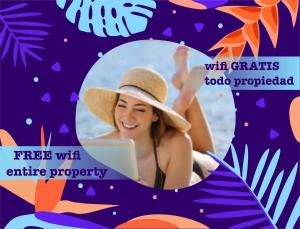 a woman in a hat sitting on the beach with a laptop at TROPICAL RETREAT SUITES at PLAYA LOS CORALES in Punta Cana