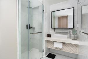 a bathroom with a shower and a sink and a mirror at Oakwood Studios Sukhumvit Bangkok in Bangkok