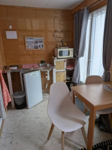 a kitchen with a table and a white refrigerator at Studio bois avec jardinet in Parentis-en-Born
