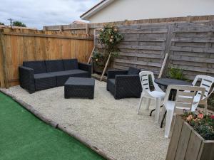 a patio with a couch and chairs and a table at Studio bois avec jardinet in Parentis-en-Born