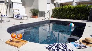 a swimming pool with two glasses and a beach ball at B&B Hotel Villa Nora in Bellaria-Igea Marina