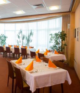 ein Restaurant mit weißen Tischen und Stühlen sowie orangefarbenen Servietten in der Unterkunft Hotel Krek Superior in Lesce