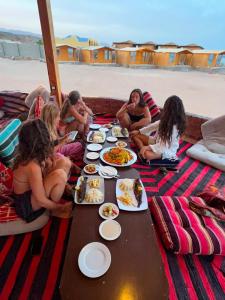 a group of people sitting around a table eating food at Marhaba Camp in Nuweiba