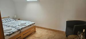 a small bedroom with a bed and a chair at Penzion Bernardýn in Bořetice +3 photos